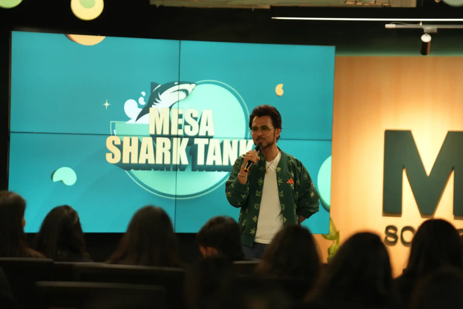 A presenter on stage at a Mesa Shark Tank session at Mesa School of Business